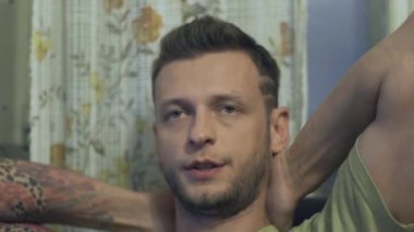 Genç bir çocuk bir sandalye ve konuşuyor, ellerini kafasının arkasında oturuyor