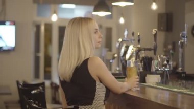 Genç sarışın kadın bir barda bir bardak bira içme