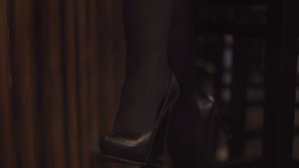 Молода блондинка в чорному взутті сидить на стільці в барі — стокове відео