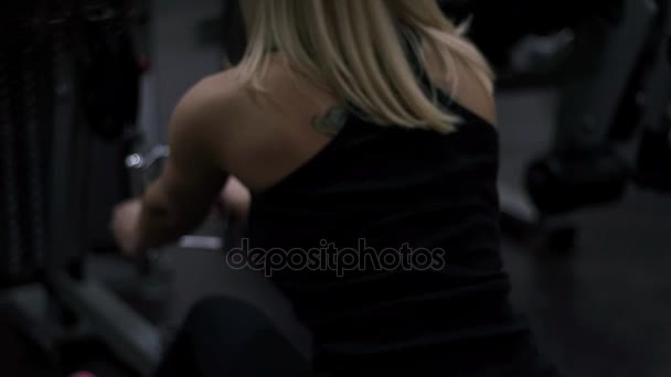 Блондинка тренируется в спортзале. Женщина занимается фитнесом — стоковое видео