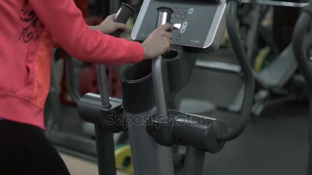 Chica rubia entrenando en el gimnasio en la elíptica — Vídeo de stock