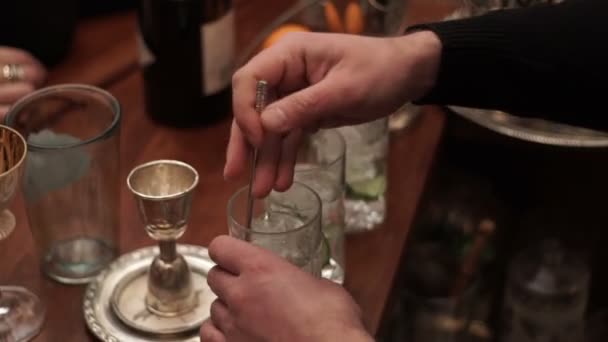 Μπάρμαν αρσενικό ανακατώνει πάγο με ένα κοκτέιλ σε ένα ποτήρι — Αρχείο Βίντεο
