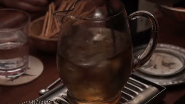 Un uomo mescola il ghiaccio in un drink in un decanter — Video Stock