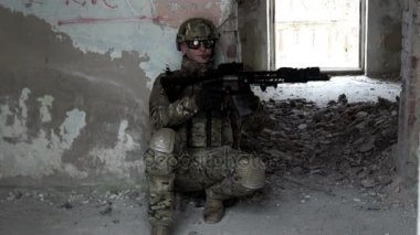 Bir silah olan askeri bir adam terk edilmiş bir binada pusuya