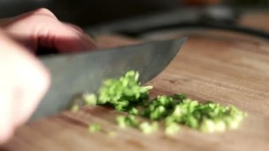 Kadın ahşap tahta üzerinde maydanoz bıçak kesiyor. Yemek yemek. Gıda katkı maddeleri