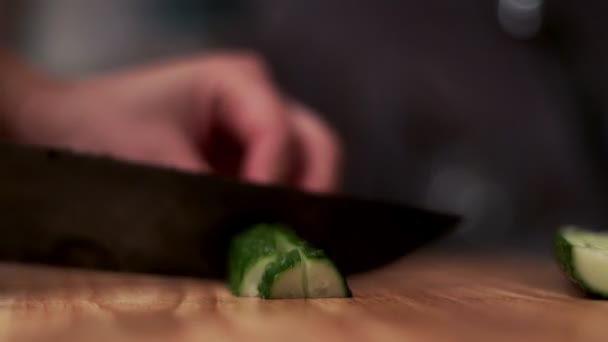 Руки женщины режут свежий огурец ножом на деревянной доске — стоковое видео