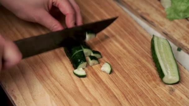 Female hands cut a fresh cucumber on wooden board with a knife — Stock Video