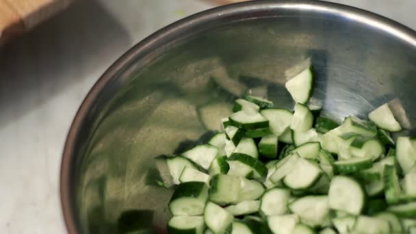 Kochmesser schmatzt Salat in Schüssel mit Gurken. Zutaten vegetarische Kost — Stockvideo