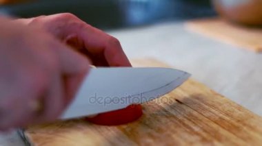 Mens ahşap tahta üzerinde bir domates kesmek şefler eller. Sebze salatası hazırlanması