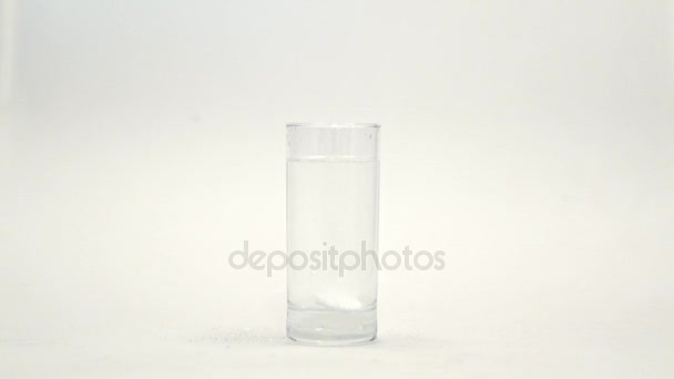 Šumivé bílé tablety ve sklenici vody na bílém pozadí. Šumivé tablety — Stock video