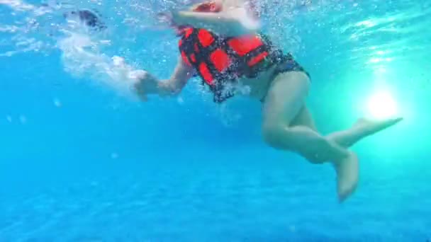 Children swimming in pool under water. Baby in life vest swims in pool — Stock Video