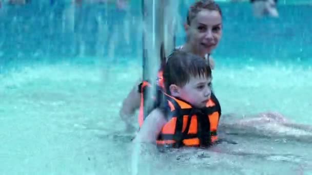 Mamá e hijo jugando en la piscina. Slow motion hijo y madre en piscina de agua — Vídeos de Stock