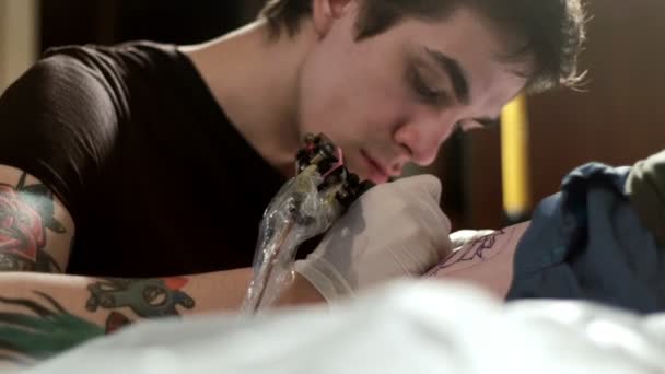 Tattooist does tattoo to a client in a tattoo parlor — Stock Video