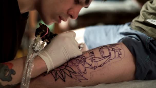 Tatuagem tatuadora faz tatuagem de um cliente com uma máquina de tatuagem — Vídeo de Stock