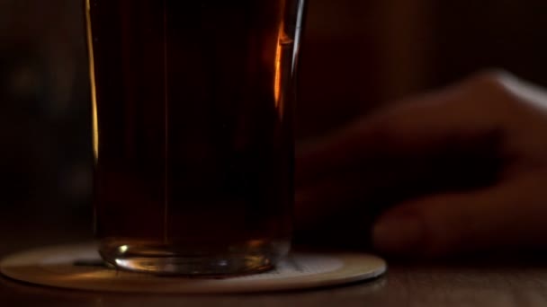 Birra di vetro in piedi sul tavolo su sfondo femminile mano toccando le dita — Video Stock