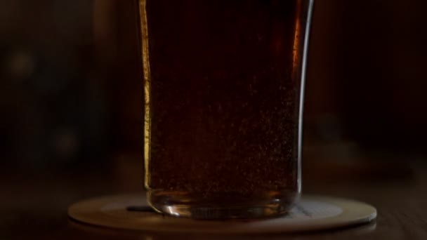 Пивний келих стоїть на столі. Пиво вливається в склянку, стоячи на столі в бар-пабі — стокове відео
