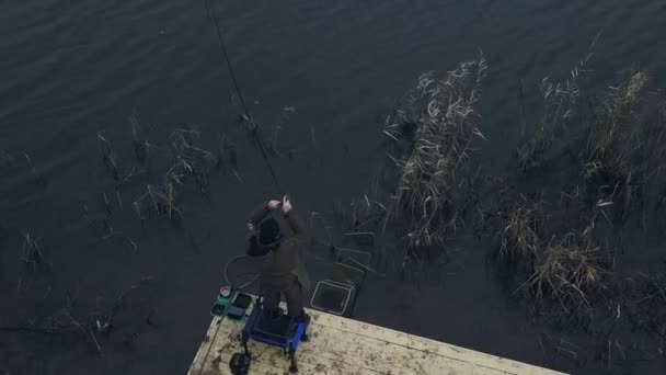 Рыбак с беспилотника крутит катушку рыбалки во время укуса на фоне реки — стоковое видео