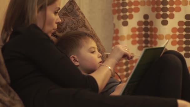 Jonge moeder samen zoontje lezen van een boek liggend op bed in gezellige slaapkamer — Stockvideo