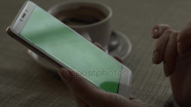 Yeşil dokunmadan kadın el cep telefonu arka plan kahve Kupası ekran