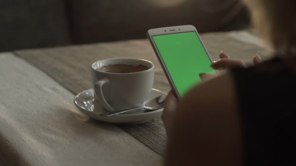 Mujer manos tocando en el teléfono móvil de pantalla verde en la taza de café de fondo — Vídeo de stock