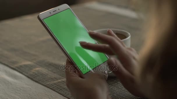 Frau tippt auf grünem Bildschirm Handy auf Hintergrund Kaffeetasse — Stockvideo