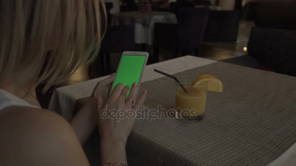 女性手背景オレンジ ジュースのグラスに緑色の画面携帯電話に触れる — ストック動画