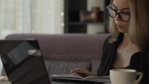 Business woman writing in diary and using notebook in co working space — Stock Video