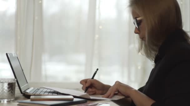 Young businesswoman in glasses signing documents and working notebook in cafe — Stock Video