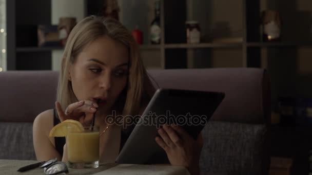 Bella donna che beve succo d'arancia dal vetro e digita sullo schermo tablet pc — Video Stock