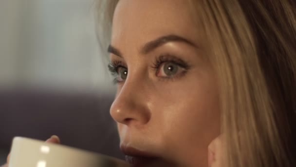 Portret jonge vrouw met blonde haren en perfecte make-up drinken koffie of thee — Stockvideo