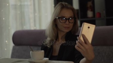 Selfie cep telefonu üzerinde öğle yemeği sırasında trendy kafede yapma gözlüklü genç kadın