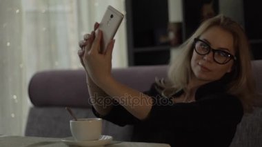 Selfie cep telefonu üzerinde öğle yemeği sırasında trendy kafede yapma gözlüklü genç kadın