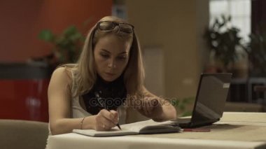 Günlüğüne yazma ve ekran dizüstü modern ofis arayan iş kadını