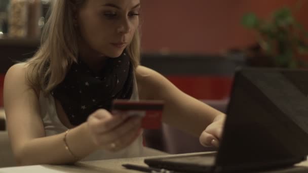 Belle femme utilisant une carte en plastique et un ordinateur portable pour faire du shopping en ligne sur Internet — Video