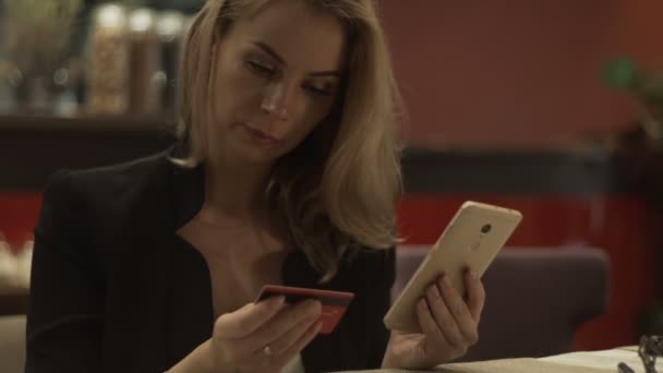 Hermosa mujer usando tarjeta bancaria de plástico y teléfono móvil para compras en línea — Vídeos de Stock