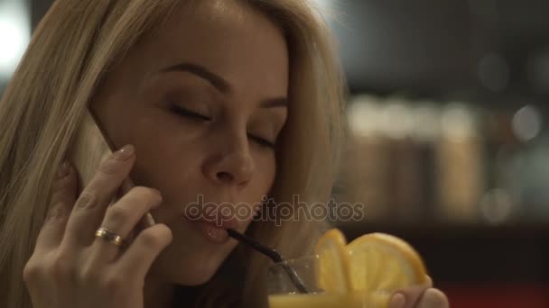 Retrato de mujer joven llamando por teléfono móvil y beber jugo de naranja — Vídeos de Stock