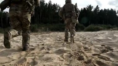 Askeri silah kum üzerinde çalışan askerlerle arkadan görünüm. Asker