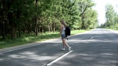 Genç kadın sırt çantası ile yol çapraz. Yolda yürürken kadın