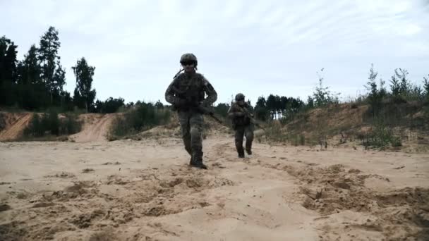 Militära soldater med vapen som slåss på bakgrunden sand. Soldater som kör — Stockvideo