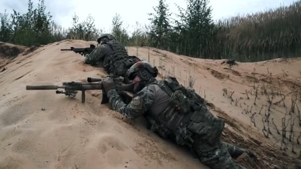 Vojenské vojáci s odstřelovací puškou ležící v záloze na písek boční pohled — Stock video