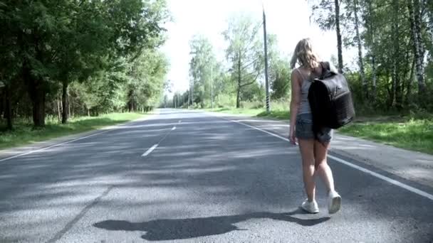 Jeune femme avec sac à dos marchant sur la route vue arrière — Video