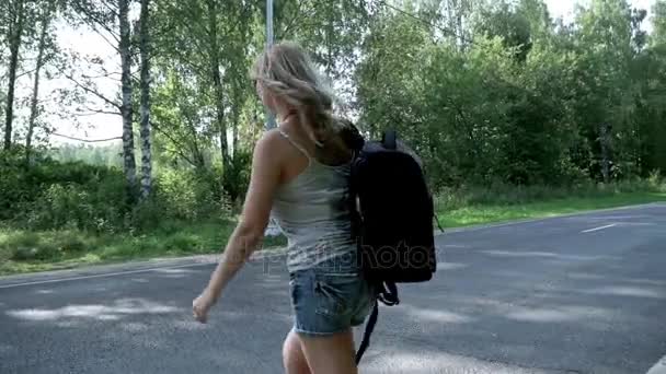 Young woman with backpack and sunglasses crossing the road — Stock Video