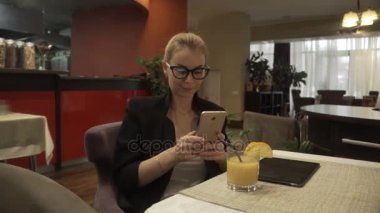 Cep telefonunuzun arka plan iç kafe üzerinde gözlük gülümseyen kadın