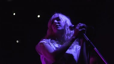 Güzel bir kadın şarkıcı dans ve rock müzik konserinde müzisyenler