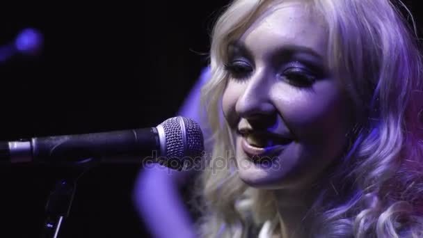 Портрет красивої жінки-співачки спереду мікрофон на рок-концерті в темряві — стокове відео