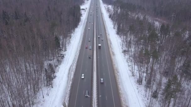 Carros e caminhões dirigindo na estrada de inverno através da vista aérea da floresta nevada — Vídeo de Stock