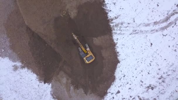 Excavadora de vista de drones trabajando en área industrial en suelo nevado — Vídeos de Stock