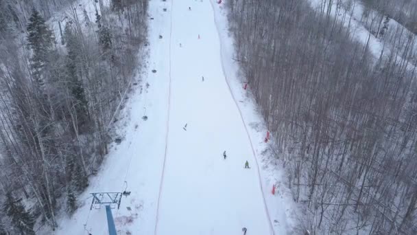 Personas esquiando y haciendo snowboard en pistas nevadas pasando el telesilla en la estación de esquí — Vídeo de stock