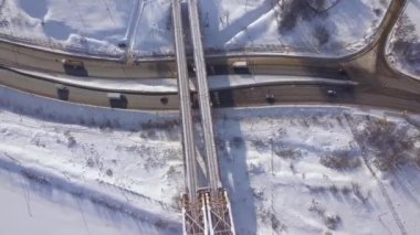 Otomobil ve kargo kamyon altında kış karayolu üzerinde hareketli köprü dron görünümü tren. Kış manzara karlı yolda araba trafik. Havadan görünümü süspansiyon demiryolu Otoban yolu üzerinden köprü.