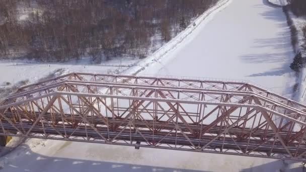 Top view suspension railway bridge for train movement over frozen river on winter landscape. Aerial view train bridge through winter river. — Stock Video